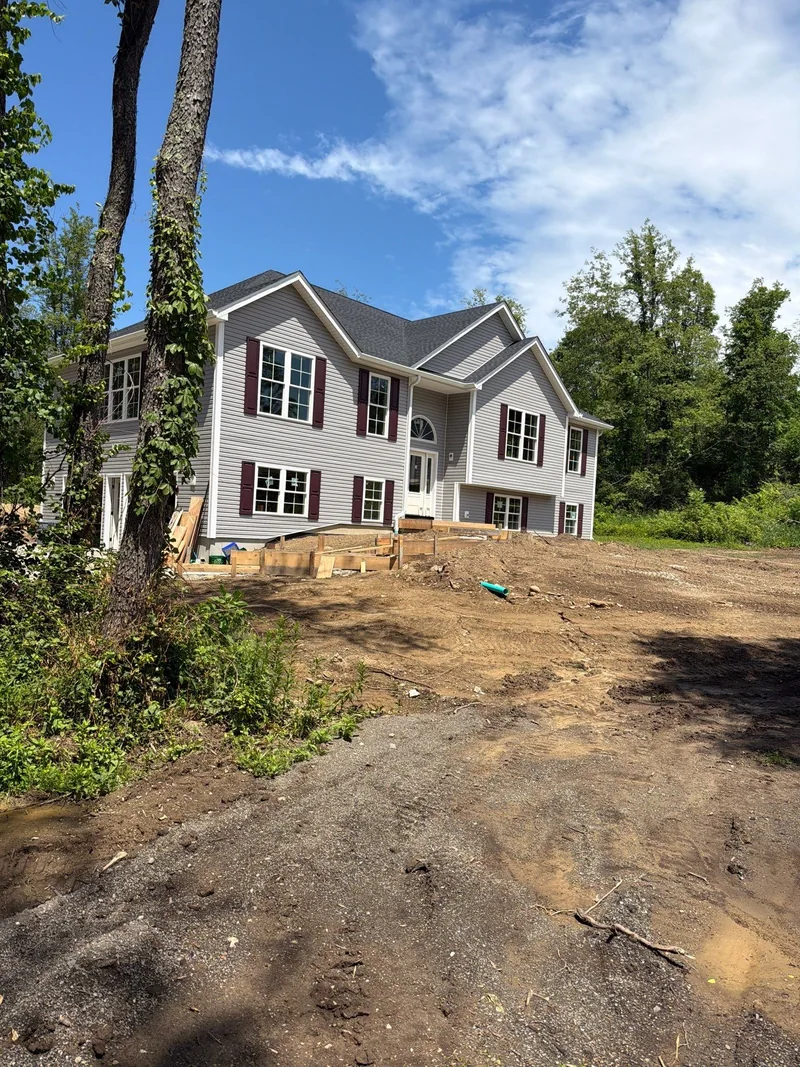 CPG-installed light gray siding and white trim on a house with burgundy shutters and unfinished landscaping